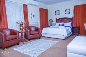 a bedroom with a bed and two chairs at Royal Highness Lux Guesthouse in Carletonville