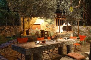 ネオ・キリマにあるEvaggelia Studiosの庭の大きな石のテーブル(オレンジの椅子付)