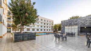 a courtyard with chairs and a tree and a building at African Sky Ermelo Inn in Ermelo