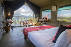 a bedroom with a bed with a view of the water at Madulkelle Tea and Eco Lodge in Kandy
