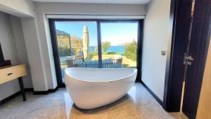 a white bath tub in a room with a large window at Çimentepe Residence Deluxe 2 - Villa with Jacuzzi in Yalikavak in Bodrum City +29 photos