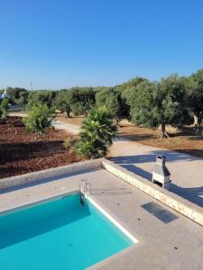 a swimming pool with a view of a road and trees at Villa Dolce Far Niente Ostuni in Ostuni