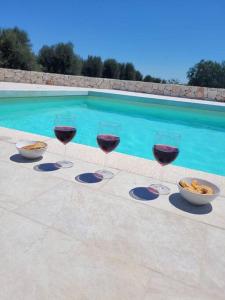 three glasses of red wine next to a swimming pool at Villa Dolce Far Niente Ostuni in Ostuni +30 photos