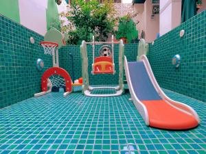 un parque infantil con equipo de juegos en el suelo de baldosa en Morocco Green House Forest en Huidong