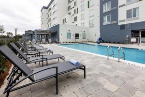 彭薩科拉的住宿－Courtyard by Marriott Pensacola West，一座带躺椅的游泳池位于大楼旁