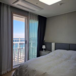 1 dormitorio con cama y vistas a un balcón en Yangyang Ocean Stay, en Yangyang
