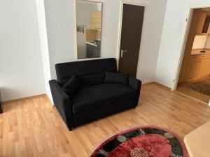 um sofá preto numa sala de estar com um tapete em Wohnung in Sankt Englmar Nr 512 em Sankt Englmar