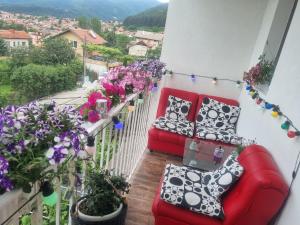 un balcón con 2 sofás rojos y flores en Guesthouse Jasmin, en Sapareva Banya