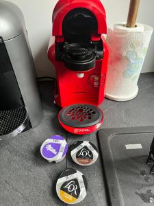 une cafetière rouge assise sur un comptoir avec des autocollants dans l'établissement Maison chaleureuse avec son bain enchanté !, à Mesnil-Saint-Père