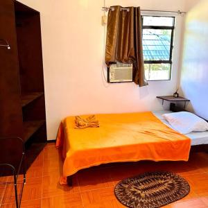 a bedroom with an orange bed and a window at Palm House in Puerto Galera