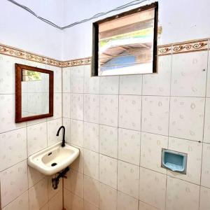 ein Bad mit einem Waschbecken und einem Spiegel in der Unterkunft Palm House in Puerto Galera