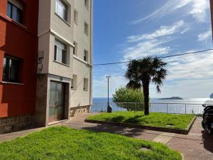 a building with a palm tree in front of the water at Tonpoigane in Bermeo