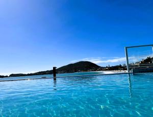 a swimming pool with blue water and a mirror at Bombinhas Tourist Apart in Bombinhas