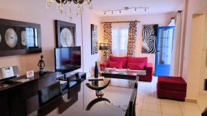 sala de estar con sofá rojo y TV en Evita Beach Suites Exclusivas en Caleta de Sebo