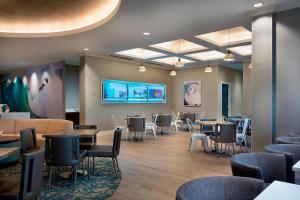 a waiting room with tables and chairs and a tv at SpringHill Suites by Marriott New Smyrna Beach in New Smyrna Beach