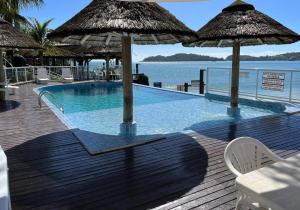a swimming pool with umbrellas on a wooden deck at Bombinhas Tourist Apart in Bombinhas