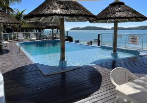 einen Pool mit Sonnenschirmen auf einer Holzterrasse in der Unterkunft Bombinhas Tourist Apart in Bombinhas