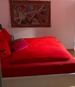 uma cama vermelha com almofadas vermelhas num quarto em 1 - 2 Zimmer in historischem Altstadthaus em Freudenstadt