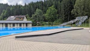a swimming pool with a slide next to a house at Berghaus Weissbriach in Weissbriach