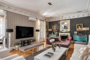 uma sala de estar com um sofá e uma televisão em HoHomes - Luxury Palacete em Barcelona
