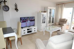 uma sala de estar com mobiliário branco e uma televisão em Apartamento en NERJA. Primera línea de playa em Nerja