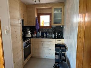 a small kitchen with wooden cabinets and a window at Chalet Edelweiss à Saint-Martin, Val d'Hérens in Saint-Martin