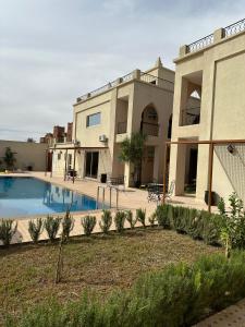 a large house with a swimming pool in front of it at Maison D'hôtes IMINIGRAN & Spa in Ouarzazate