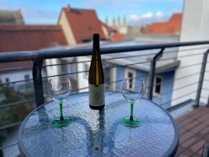 a glass table with a bottle of wine and two glasses at Brix Apartment in Naumburg