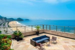 uma varanda com um sofá e cadeiras e a praia em JW Marriott Rio de Janeiro no Rio de Janeiro