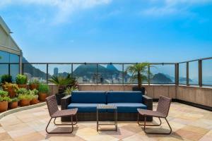 a blue couch on a balcony with two chairs at JW Marriott Rio de Janeiro in Rio de Janeiro