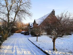 uma casa com uma entrada coberta de neve e duas árvores em Cottage en bordure bruxelloise em Wezembeek-Oppem