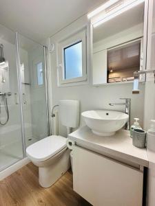 a white bathroom with a toilet and a sink at Mobile Home - Sea La Vie in Biograd na Moru