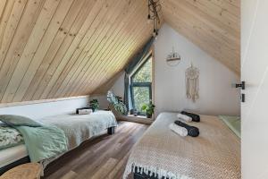 two beds in a attic bedroom with wooden ceilings at Domek Ponad Mgłami in Laskowa