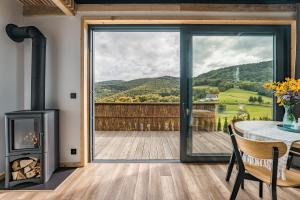 a living room with a fireplace and a table with a view at Domek Ponad Mgłami in Laskowa