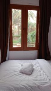 a bed with a white pillow in front of a window at Riad Nizwa in Nizwa