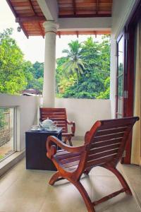 2 bancos de madera sentados en un porche con mesa en Volunteer Ceylon en Ratnapura
