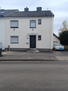 a white house with a car parked in front of it at Haus Langert - Einfamilienhaus mit Terrasse und Garten zur alleinigen Nutzung in Baesweiler