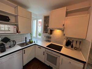 una cocina con armarios blancos y fregadero en Castle View Apartment, en Budapest