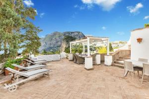 a patio with chairs and tables and a gazebo at Terrazza Tragara in Capri