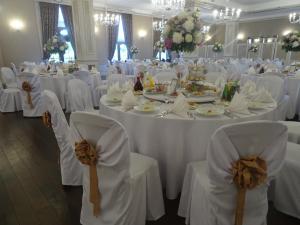 a banquet hall with white tables and chairs with bows at Pałac w Konarach in Konary