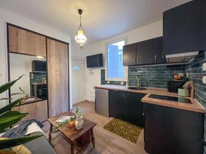 a kitchen with black cabinets and a table at Confort & modernité au centre de Tarbes in Tarbes