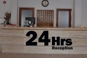 uma recepção com uma placa de recepção com horas em Tasmaria Aparthotel em Pafos