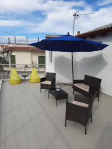 a patio with chairs and a blue umbrella at Mary's luxury apartment Nemea in Neméa
