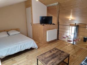 1 dormitorio con 1 cama, TV y mesa en Le Chalet, en Parthenay