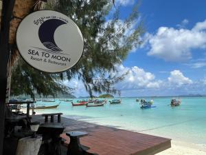 麗貝島的住宿－Sea To Moon Lipe，海滩上的标志,在水中划船