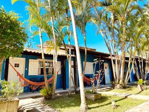 una casa azul con palmeras delante en Pousada Lagoa Encantada, en Garopaba