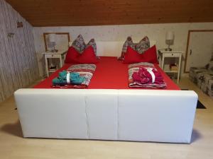 a large white bed with red pillows on it at Ferienwohnung Schäfer in Anschau