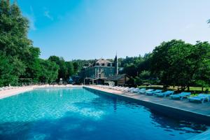 une piscine avec des chaises longues et une maison dans l'établissement Floreal La Roche-en-Ardenne, à La-Roche-en-Ardenne