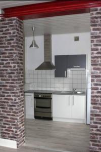 een keuken met witte apparatuur en een bakstenen muur bij Agréable F3 - RDC (2 chambres) in Mulhouse