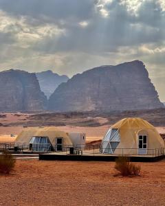 two tents in the desert with mountains in the background at desert princess luxury camp in Wadi Rum